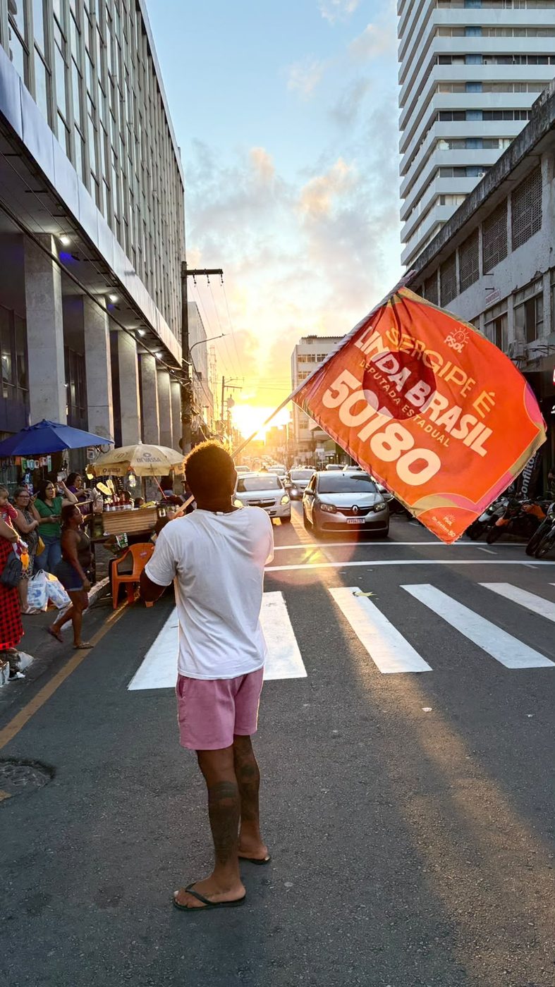 Apoiador ergue bandeira da campanha de Linda Brasil no fim da tarde, no Centro de Aracaju