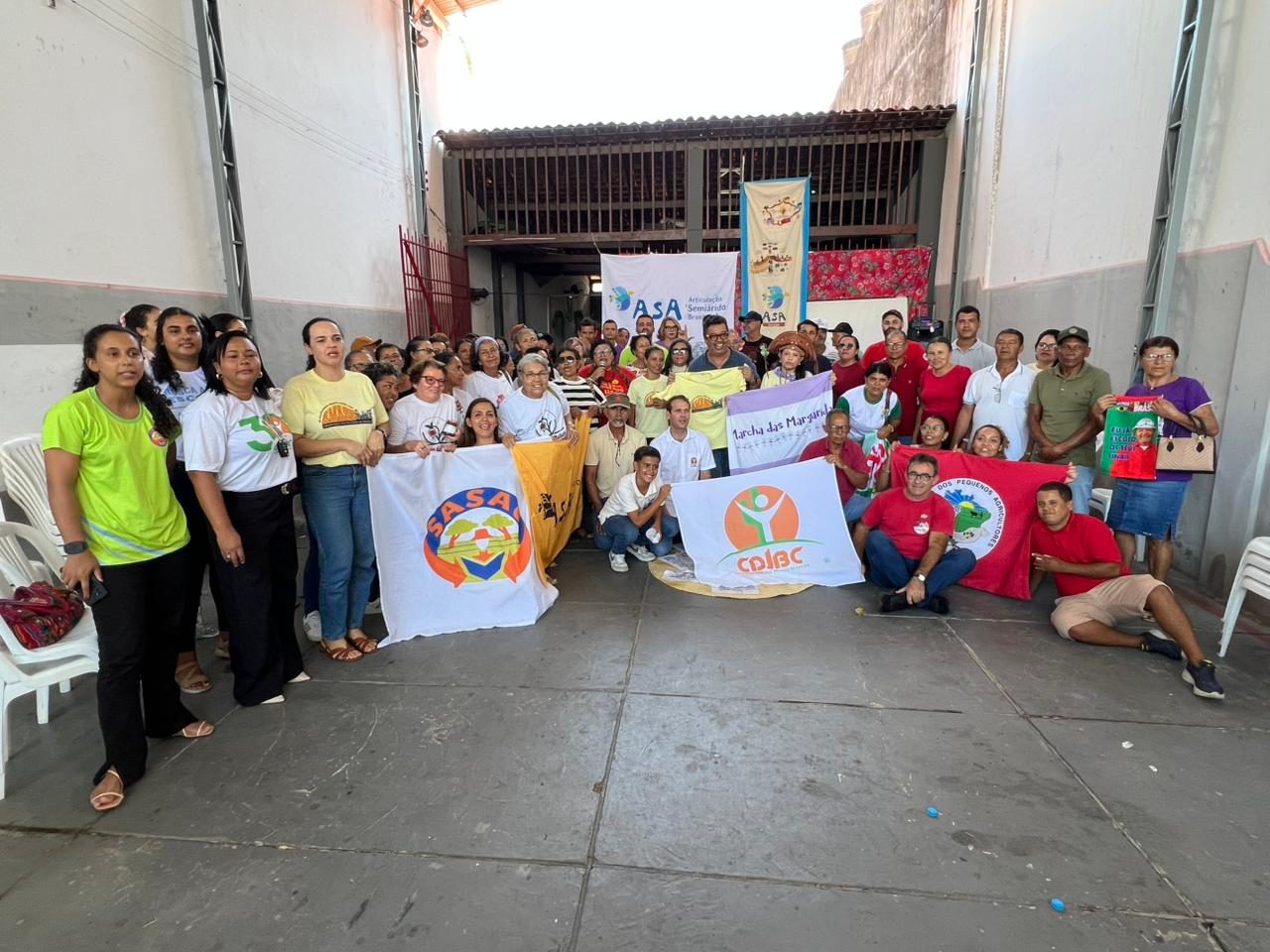 Participantes do encontro reunidos com bandeiras da ASA, da Marcha das Margaridas e do Centro Dom José Brandão de Castro
