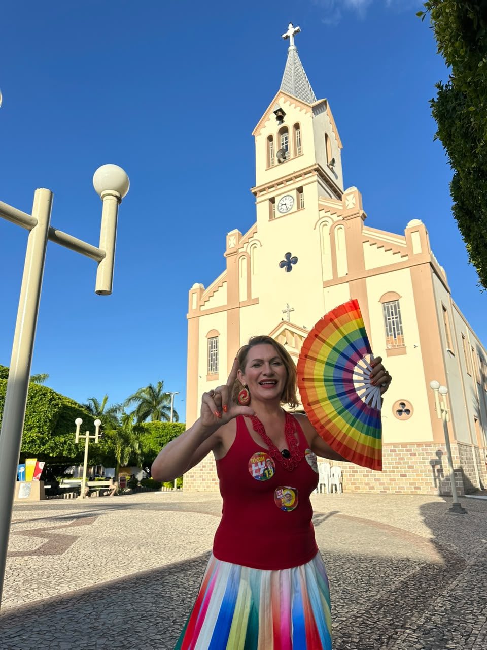 Linda Brasil com leque colorido em frente à igreja matriz de um município do interior de Sergipe